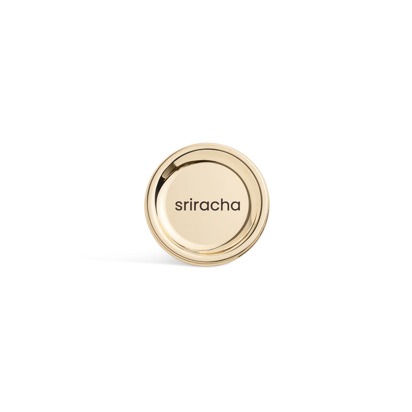 Saucie Sriracha Sauce Labelled Lid – brushed gold metal disc with laser-etched text