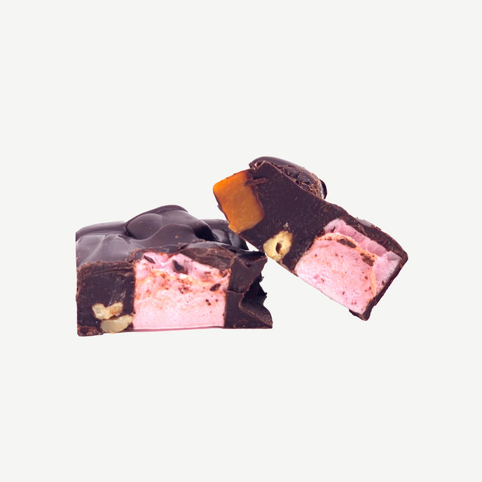 Chunky dark chocolate rocky road showing layers of marshmallows, cashews, raspberry lollies and caramel fudge pieces