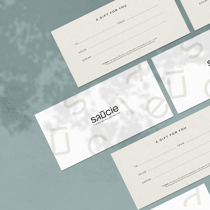 Several gift vouchers with the brand name 'saucie' laid out on a textured grey surface.