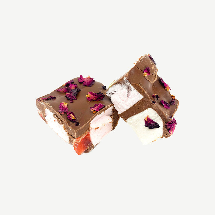Chunky rocky road showing Turkish delight pieces, pistachios, marshmallows and rose petals in milk chocolate