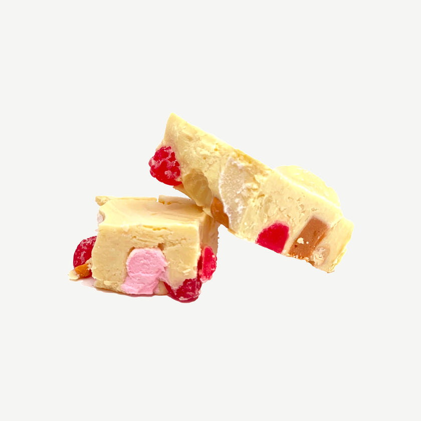 Chunky white chocolate rocky road showing marshmallows, cashews, raspberry lollies and caramel fudge pieces