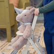 Child holding a plush toy horse on wheels in a room with furniture and a rug.