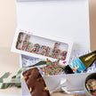 Gift box with wine, chocolate, and colorful lettered treats on a beige background