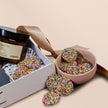 Colorful sprinkled candies in a pink bowl with a white box on a beige background