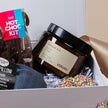 Gift box with a jar, pillow, and hot chocolate kit on a light background
