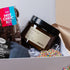 Gift box with a jar, pillow, and hot chocolate kit on a light background