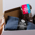 Gift Box containing a blue eye pillow and a hot chocolate kit on a light background
