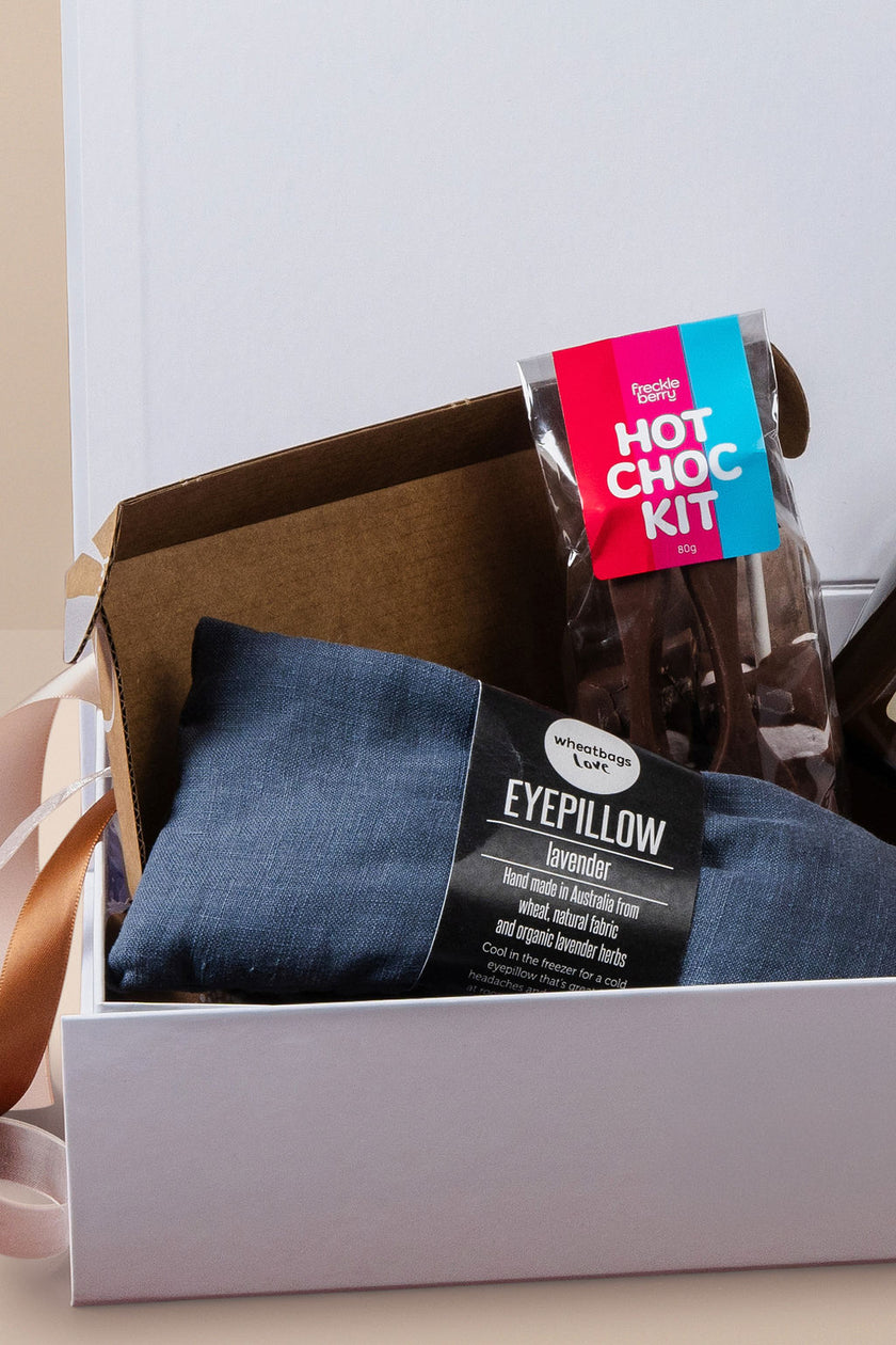 Gift Box containing a blue eye pillow and a hot chocolate kit on a light background