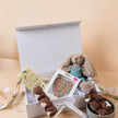 New parents opening Saucie New Baby Hamper with plush toy and handmade chocolates – thoughtful baby gift