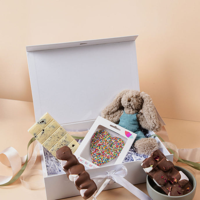 New parents opening Saucie New Baby Hamper with plush toy and handmade chocolates – thoughtful baby gift