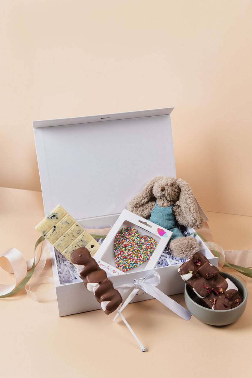 New parents opening Saucie New Baby Hamper with plush toy and handmade chocolates – thoughtful baby gift