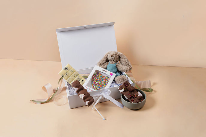 Gift box with plush toys, a small basket, and a decorative item on a beige background