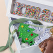Decorative Christmas-themed box with colorful letters and a tree design, featuring Freckleberry branding.