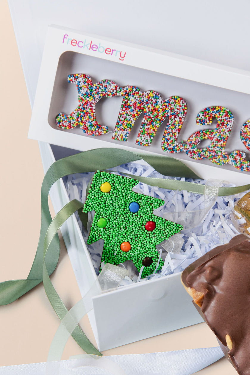 Decorative Christmas-themed box with colorful letters and a tree design, featuring Freckleberry branding.