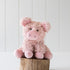 Pink plush pig toy on a wooden block with a white background