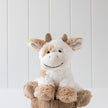 Plush cow toy on a wooden stump with a white background