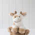 Plush cow toy on a wooden stump with a white background