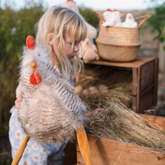Child playing with a toy chicken in an outdoor setting