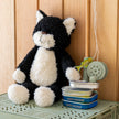 Black and white cat-shaped plush toy on a green crate with a wooden background