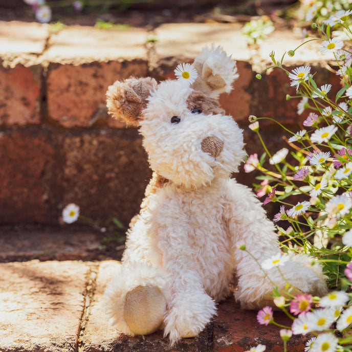 Stuffed dog toy on a brick step with flowers