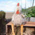 Plush toy chicken on a wooden platform with a garden background