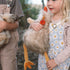 Child holding a fluffy toy with long legs outdoors. Soft chickens toy plush newborns toys