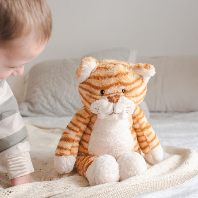 Child playing with a plush tiger toy on a bed