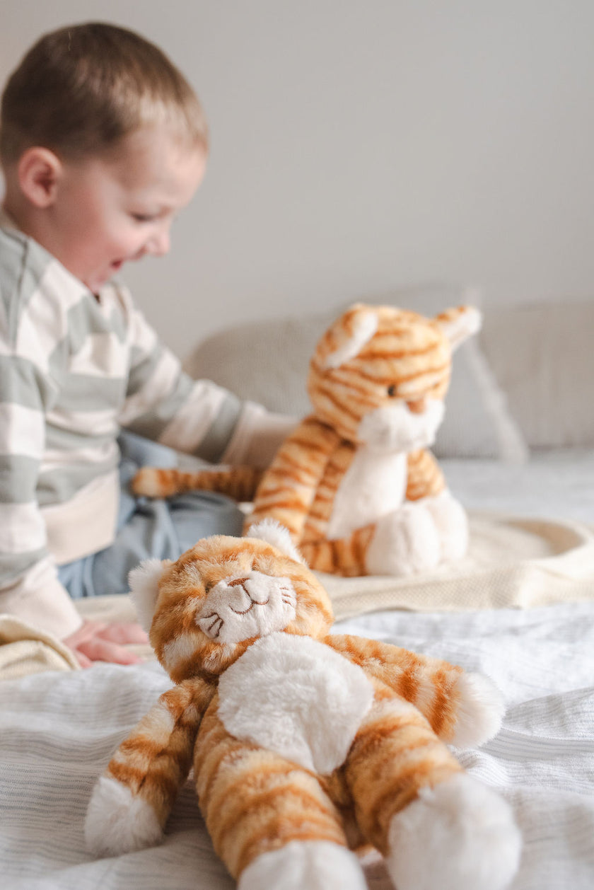 Child playing with plush tiger toys on a bed