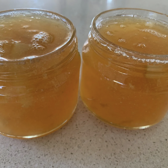 Two jars of marmalade on a speckled countertop