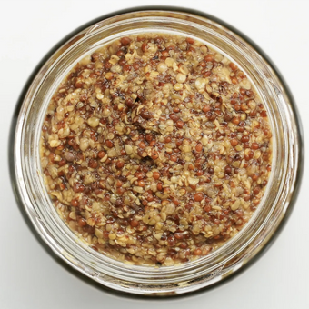 Close-up of a glass jar filled with a honey mustard on a white background