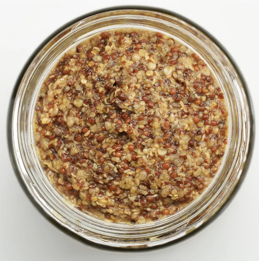 Close-up of a glass jar filled with a honey mustard on a white background