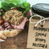 Sandwich with meat and bread, accompanied by a jar of 'Mumma's Spiced Honey Mustard' on a wooden surface.