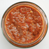 A jar of spicy tomato relish with a rich red color and visible chunky texture.