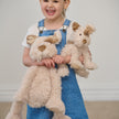 Young girl holding two teddy dogs against a plain background