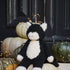 Black and white cat plush toy sitting on pumpkins with a dark background
