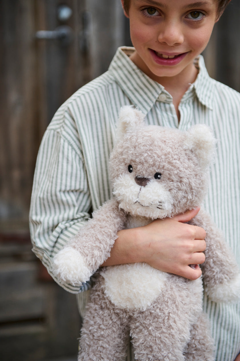 Child holding a teddy bear in an outdoor setting