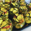 Jars of pickled vegetables including zucchini and bell peppers on a tray.