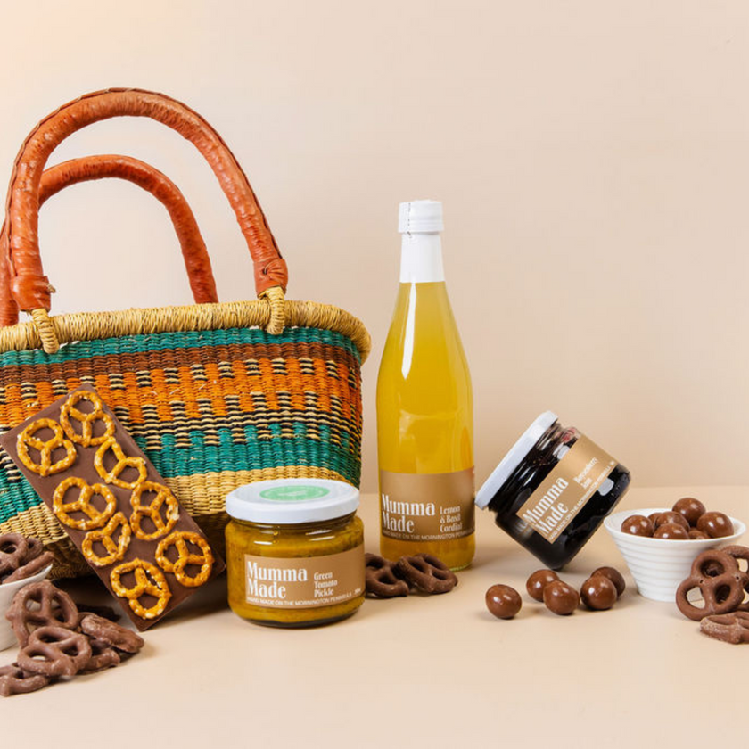 Bottle of lemonade, jar of jam, and basket with snacks on a beige background. Hamper for gifts, corporate, thank you, teachers