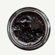 Top-down view of a jar of dark jelly or jam on a white background