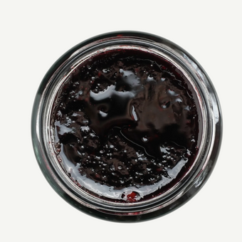 Top-down view of a jar of dark jelly or jam on a white background