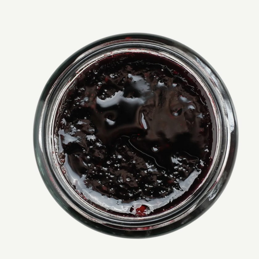 Top-down view of a jar of dark jelly or jam on a white background