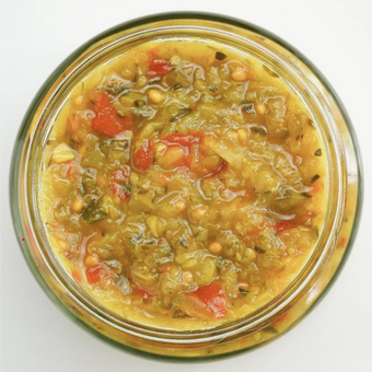 A jar of zucchini pickle with visible zucchini pieces, red pepper, and spices.