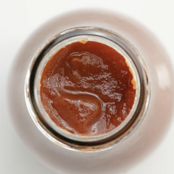 Close-up of a jar with a brown substance on a white background