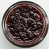 Close-up of a jar of dark relish on a white background