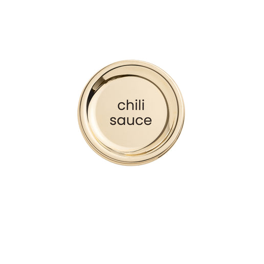 A brushed gold metal lid disc for a condiment bottle with 'chili sauce' text laser-engraved on it.