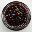 Close-up of a jar of dark berry jam on a white background