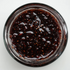 Close-up of a jar of dark berry jam on a white background