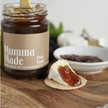 Jar of 'Mumma Made' pear paste on a wooden surface with a cracker spread with the paste.