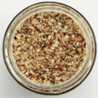 Glass jar filled with a mixture of seeds on a light gray background