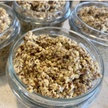 Glass jars filled with a crumbly, brownish mixture on a light surface.